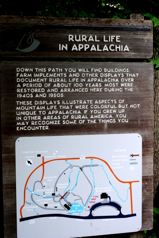 Plaque reads: Down this path you will find buildings, farm implements and other displays that document rural life in Appalachia over a period of about 100 years. Most were restored and arranged here during the 1940s and 1950s. These displays illustrate aspects of mountain life that were colorful but not unique to Appalachia. If you grew up in other areas of rural America, you may recoginze some of the things you encounter.